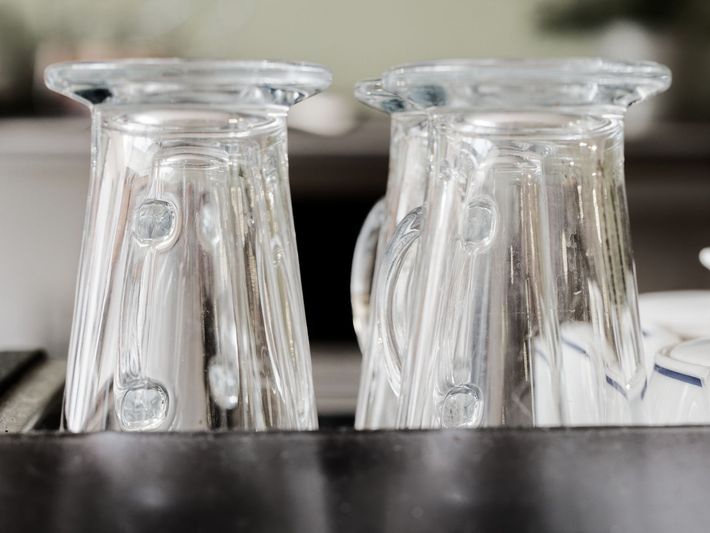 Two empty glasses are sitting on top of the espresso machine.