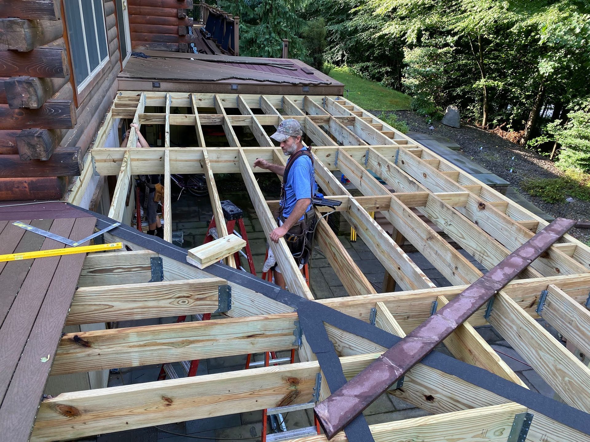A man is working on a wooden deck under construction.