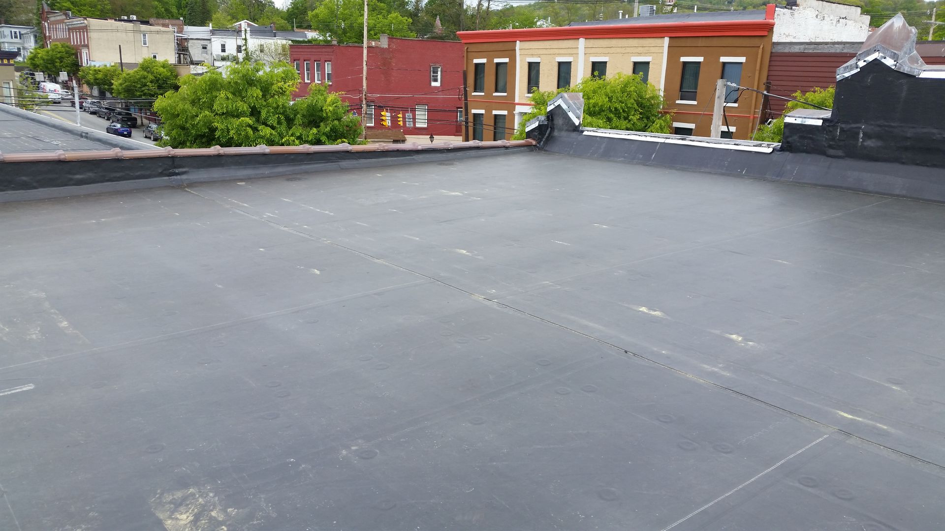 A black roof with a few buildings in the background.