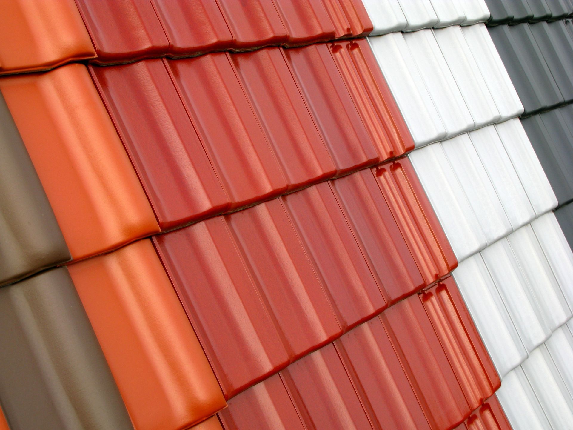 A row of roof tiles of different colors are stacked on top of each other.