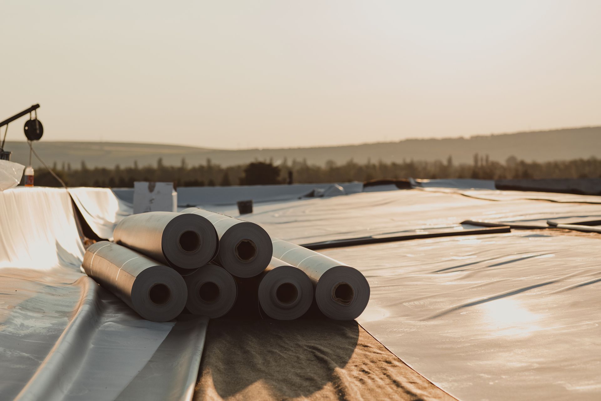 A stack of rolls of roofing material sitting on top of a roof.