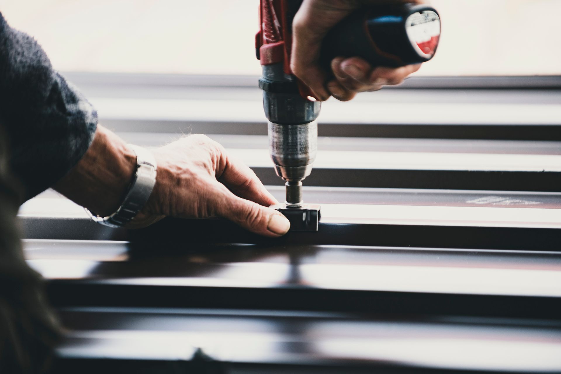 A man is using a drill to drill a hole in a piece of metal.