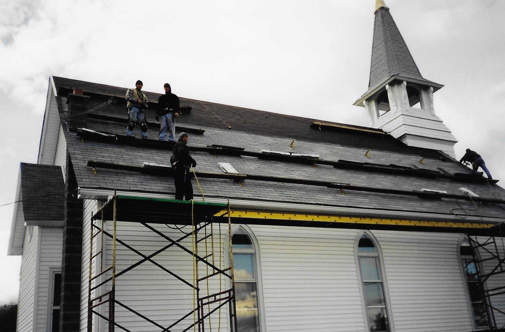 A large white house with a black roof is sitting on top of a lush green field.