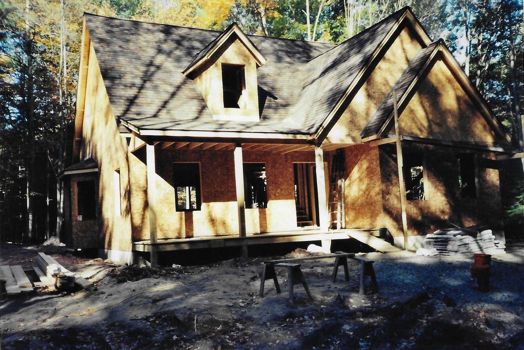 A house with a lot of leaves on the ground in front of it.