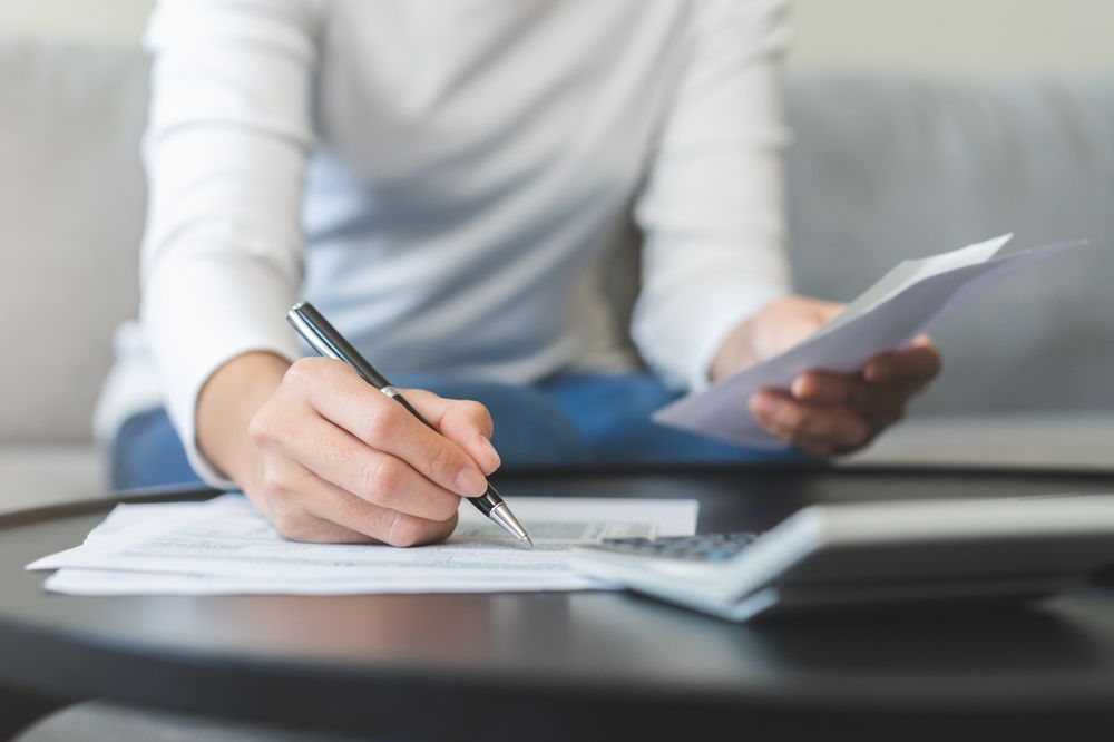 A woman is sitting at a table writing on a piece of paper.