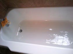 A white bathtub is sitting in a bathroom next to a wall.