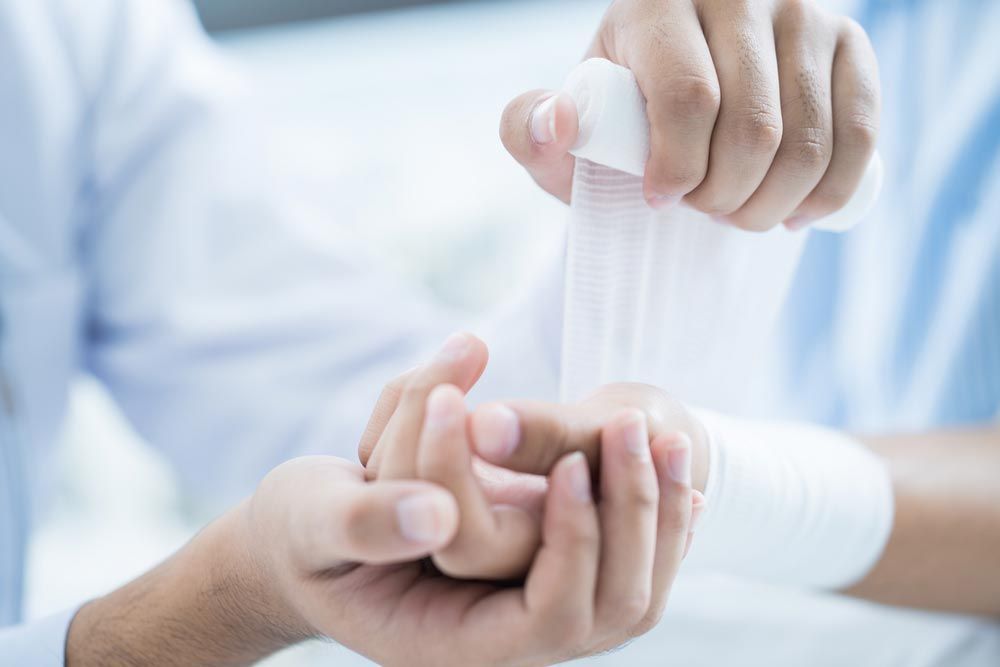 Doctor Is Bandaging a Patient's Arm — First Aid Industrial Medical In Newcastle, NSW