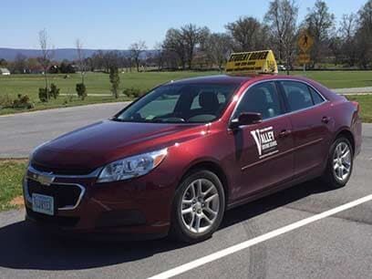 A classroom with a teacher lecturing to students on computers.