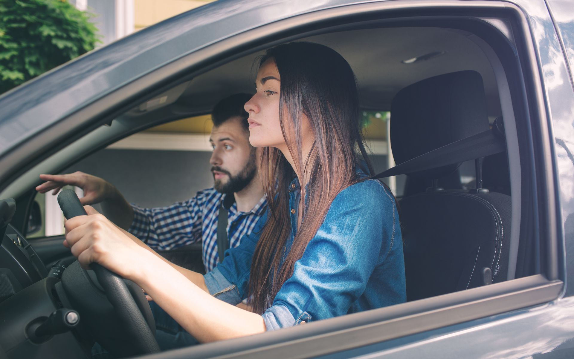 Woman driving, instructor beside her, pointing.