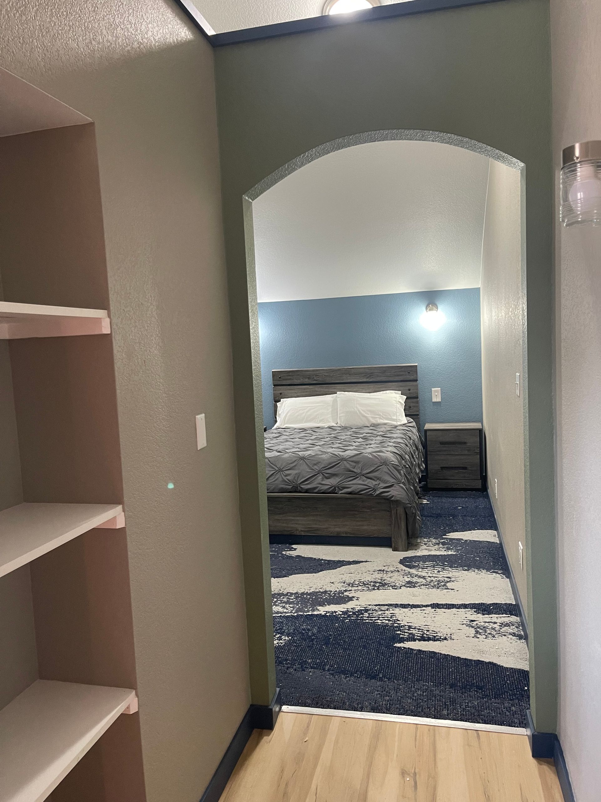 Bright hotel room with bed, leather chairs, and large windows overlooking snowy mountains.