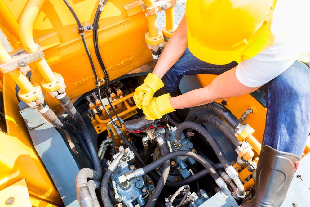 A Man in a Hard Hat is Working on the Engine of a Machine — Calibre Resourcing Solutions in Rockhampton, QLD