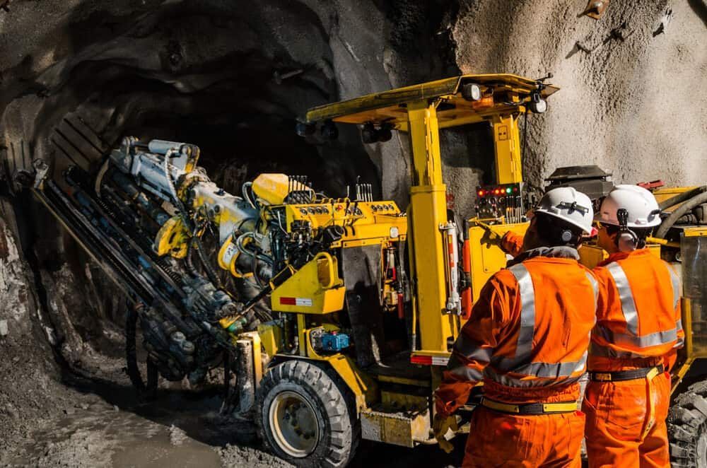 A Group of Men Are Standing in Front of a Machine in a Tunnel — Calibre Resourcing Solutions in Mount Isa City, QLD