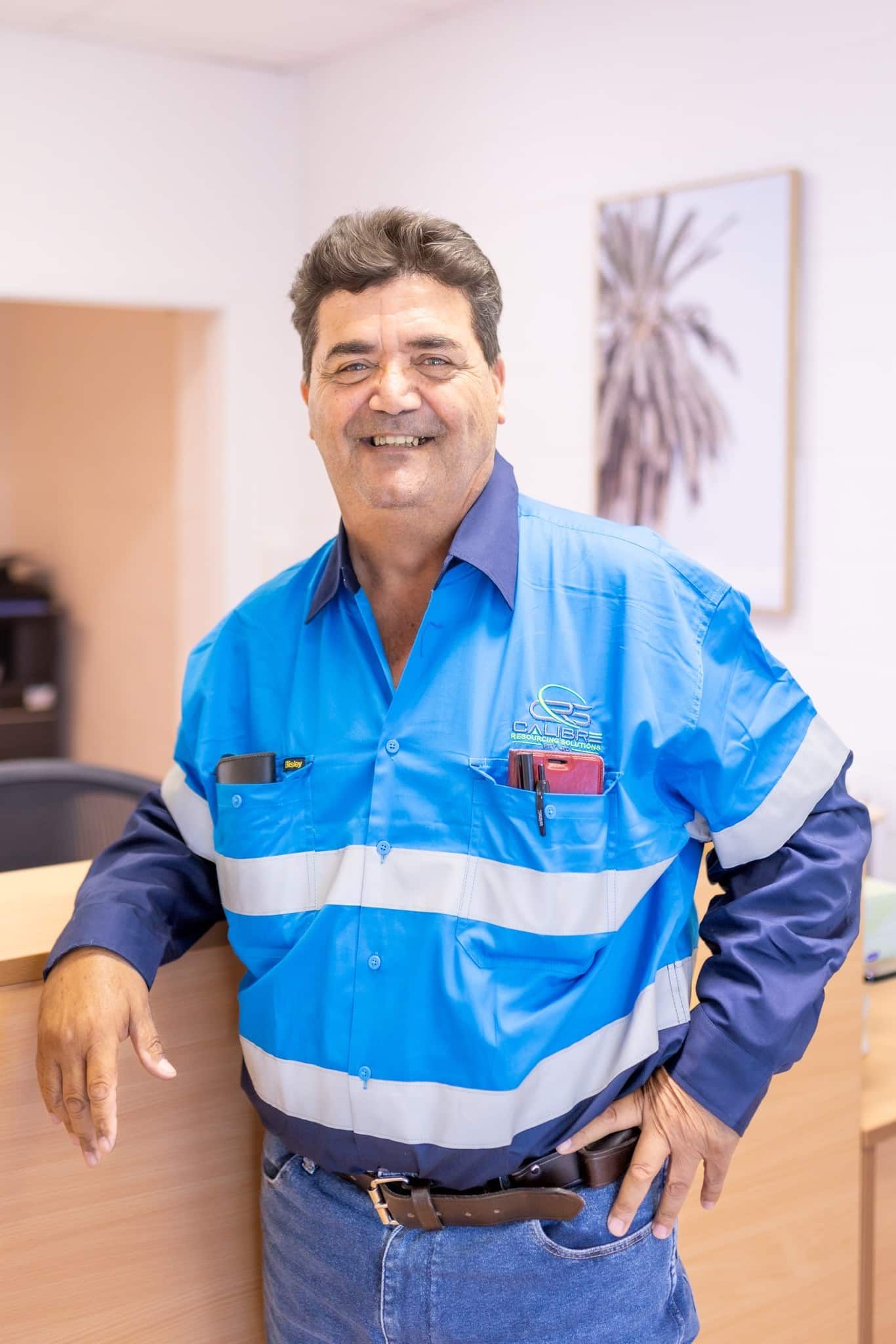 A Man in a Blue Shirt is Standing in Front of a Counter — Calibre Resourcing Solutions in Mount Isa City, QLD