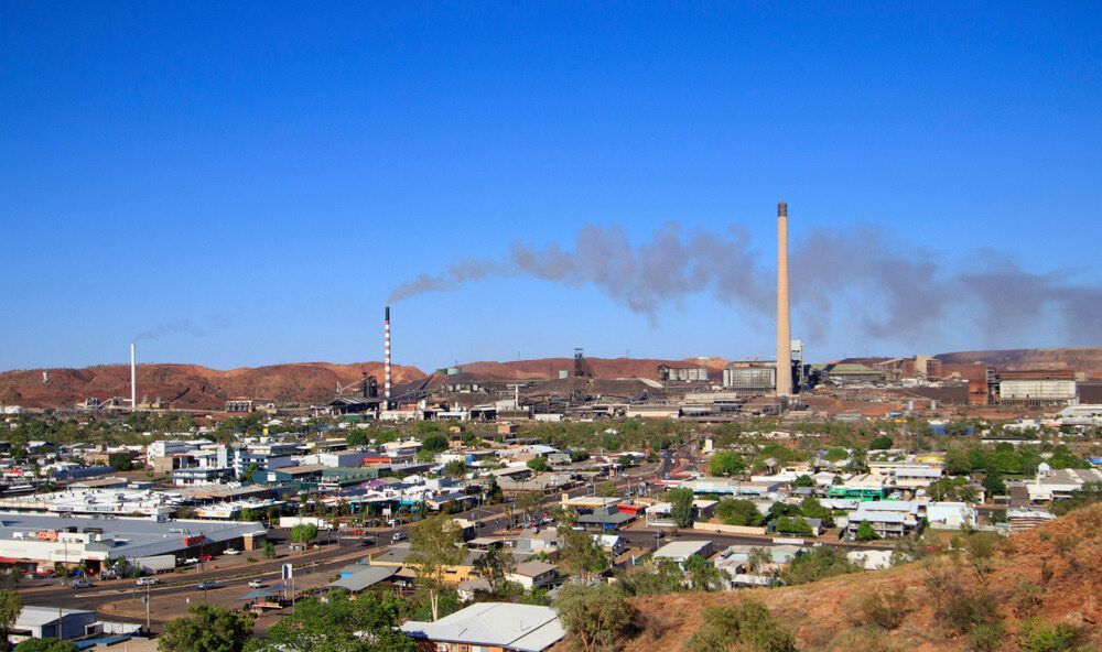A Waterfall is Surrounded by Rocks and Trees With a Blue Sky in the Background — Calibre Resourcing Solutions in Mount Isa City, QLD