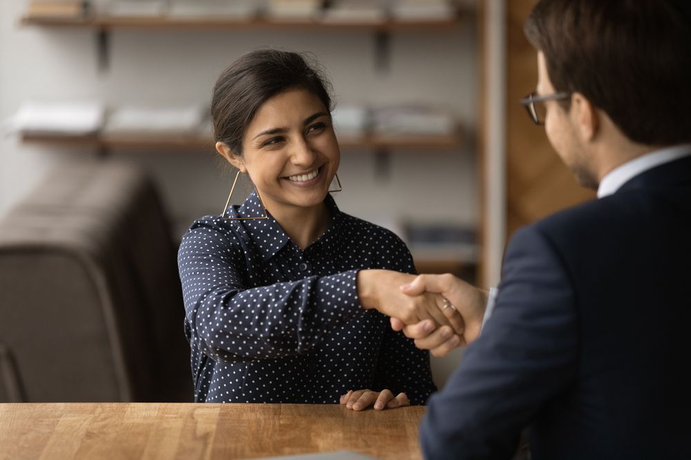 A Woman is Shaking Hands With a Man During a Job Interview — Calibre Resourcing Solutions in Townsville, QLD