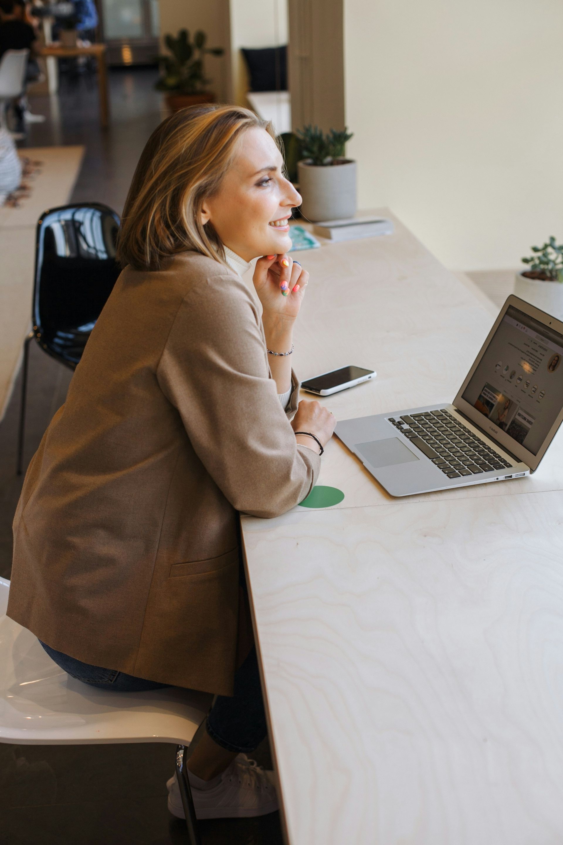 A woman is sitting at a table using a laptop computer.