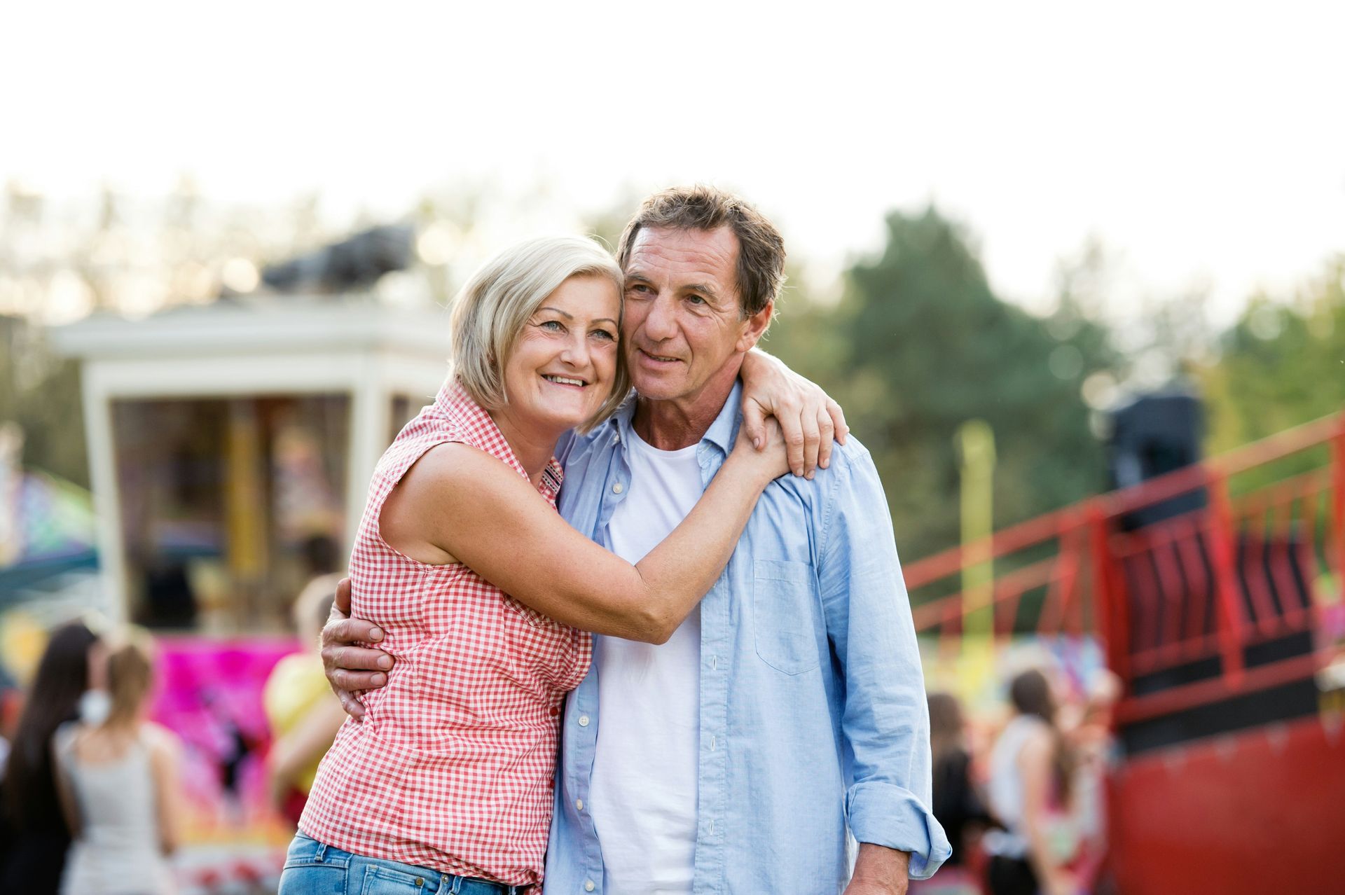 A man and a woman are sitting on a bench looking at a vineyard.