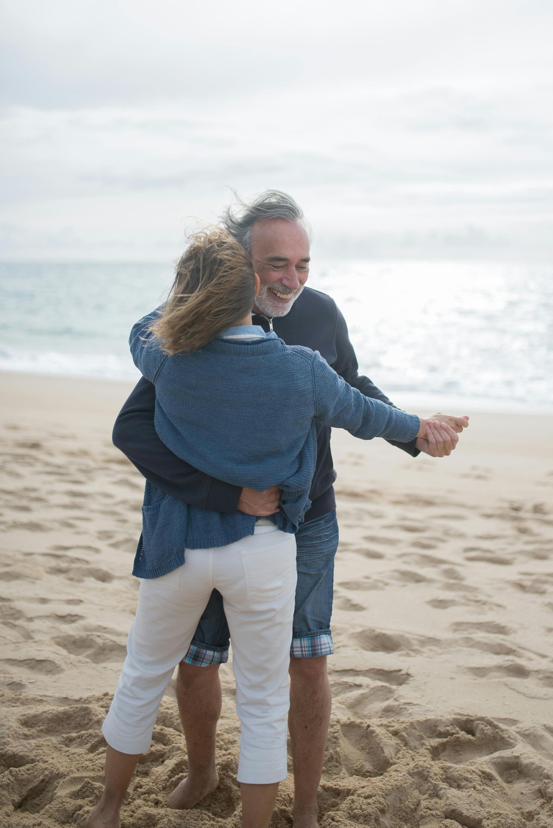 A man and a woman are dancing on the beach.