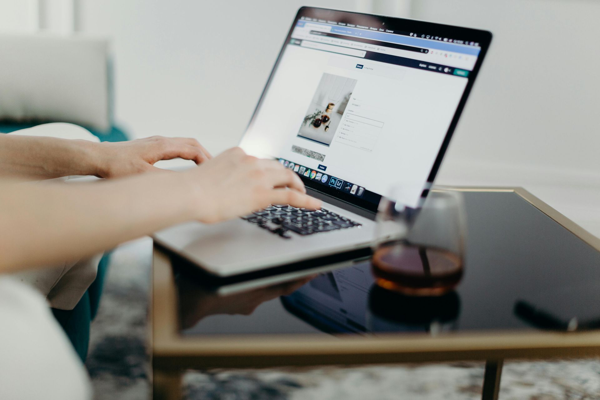 A person is typing on a laptop computer while sitting on a couch.