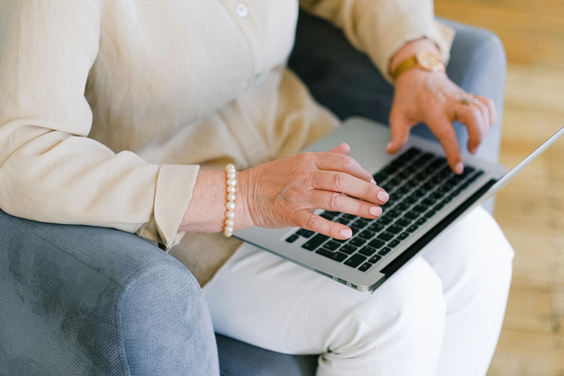 A woman is sitting in a chair using a laptop computer.