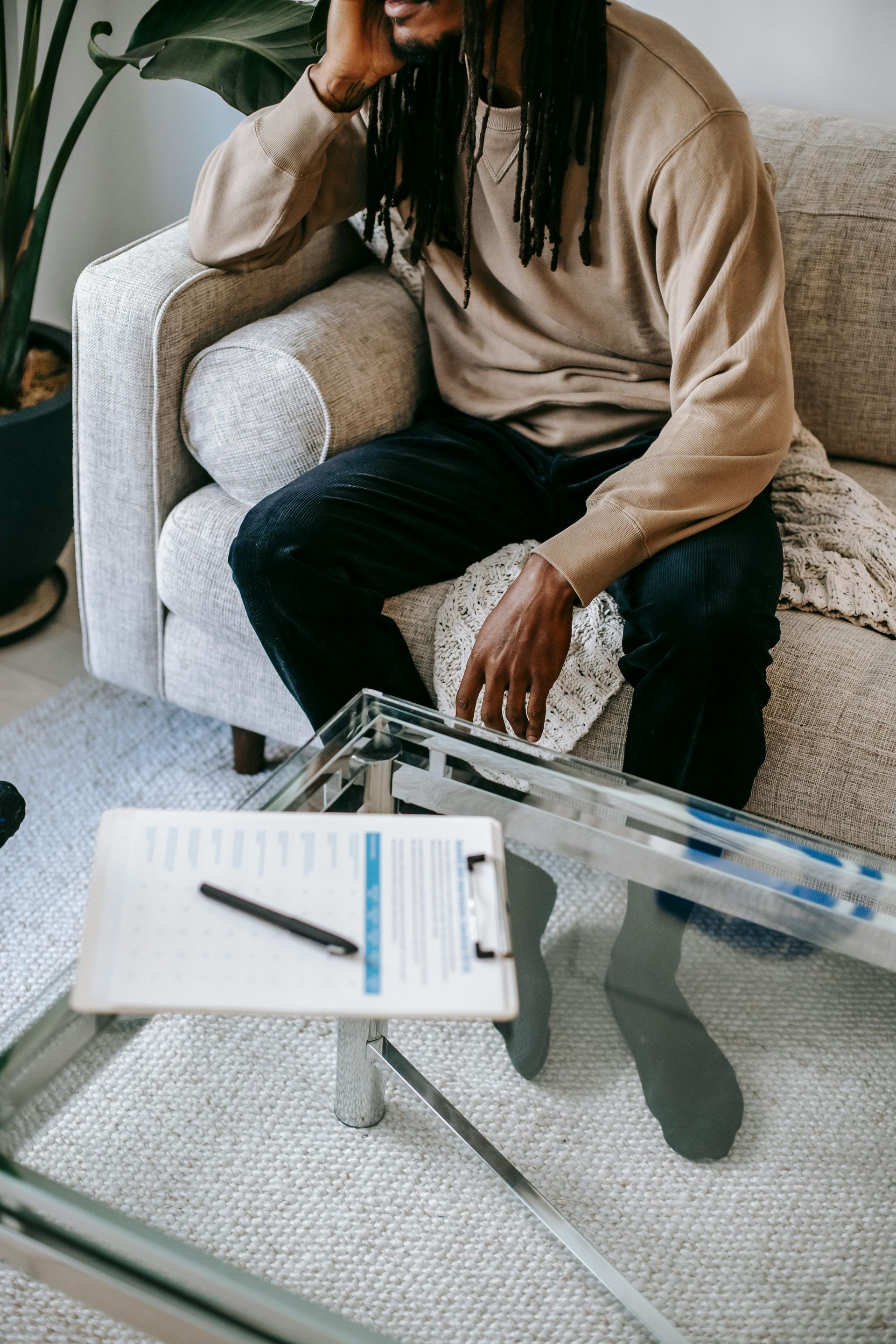 A man is sitting on a couch looking at a clipboard.
