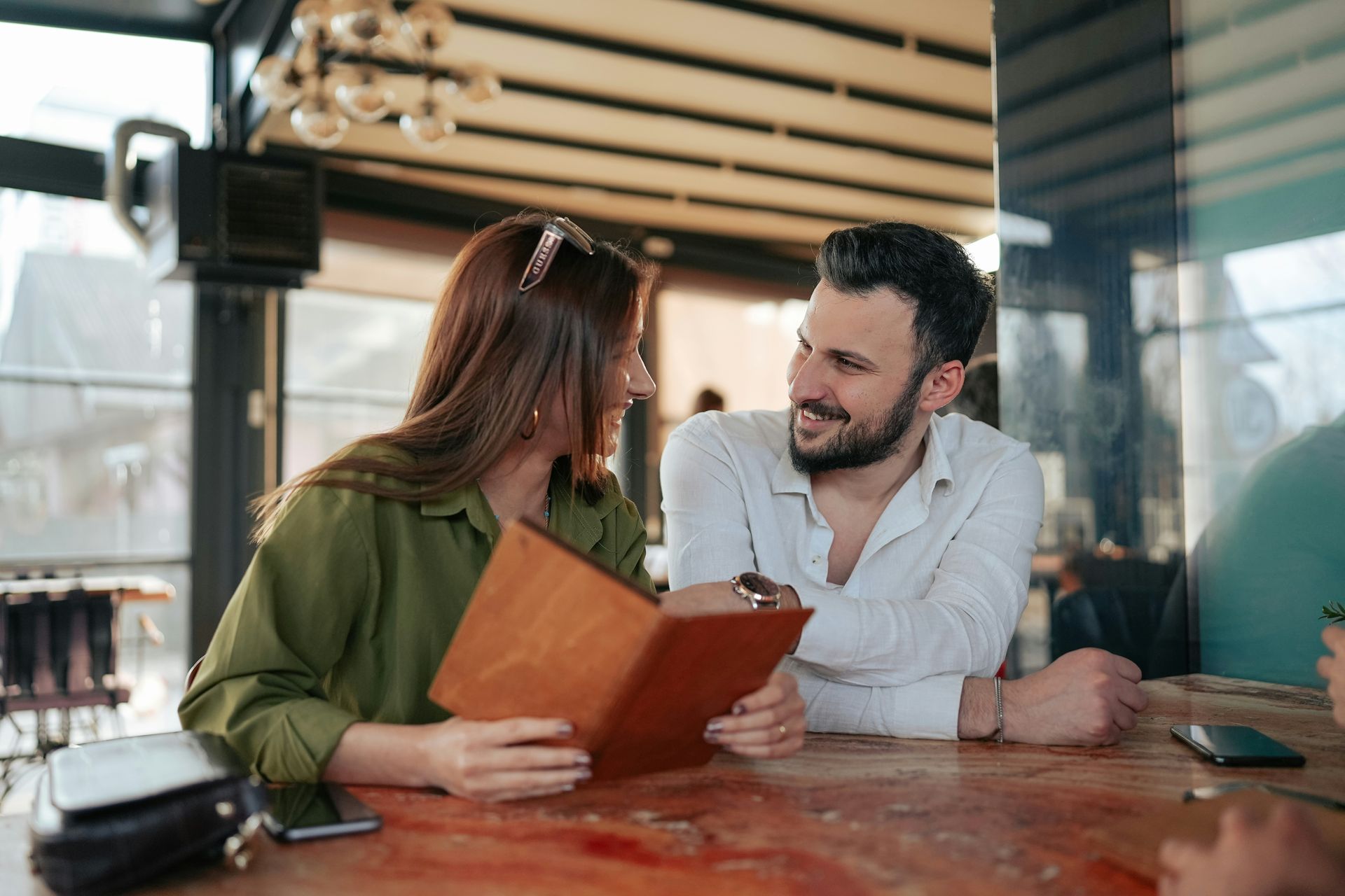 A man and a woman are sitting at a table in a restaurant looking at a menu.