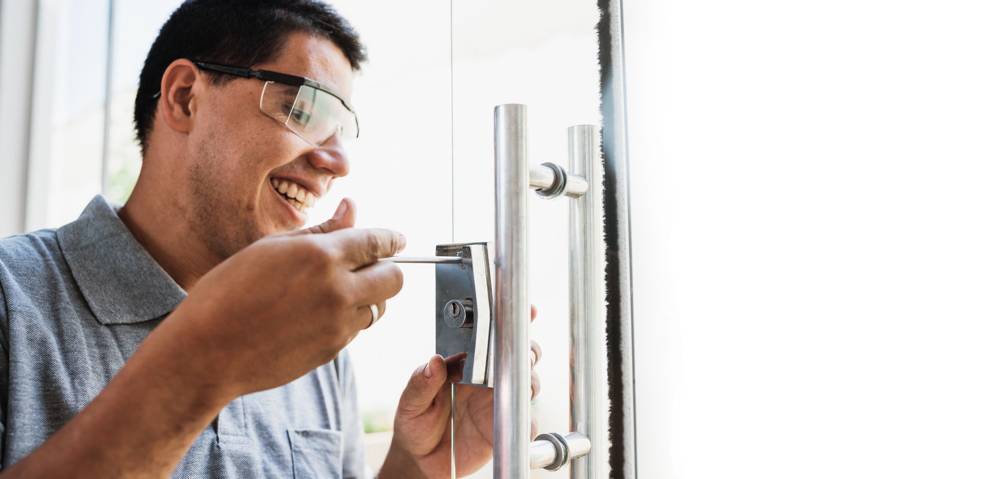 A locksmith is working on the lock of a glass door.