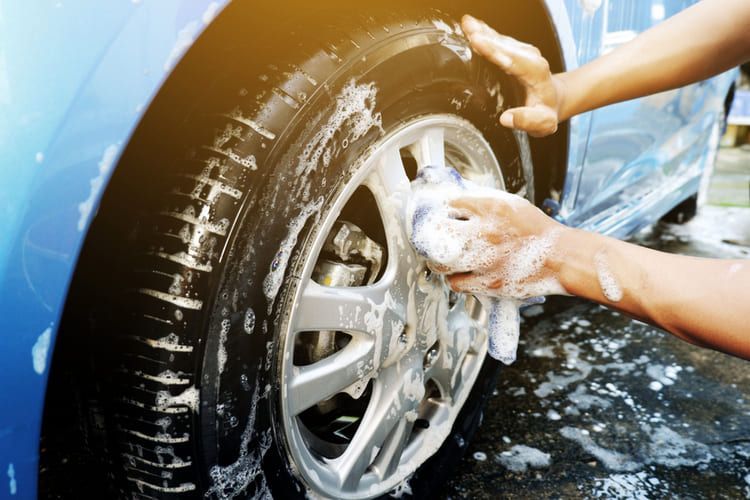 A car wheel is being washed with pH neutral shampoo and water.