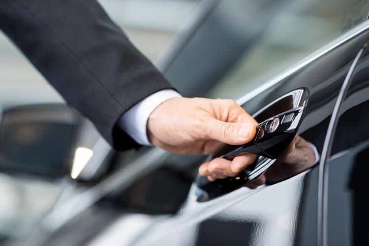 An image showing a professional workman opening the car door to a high-quality clean car.