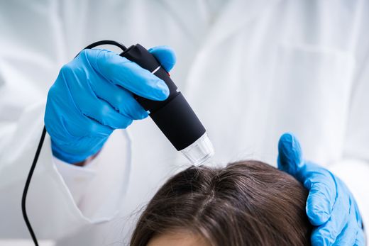 Un medico esamina i capelli di una donna al microscopio.