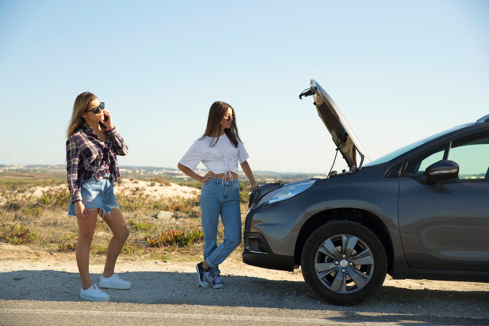 two woman standing beside the car