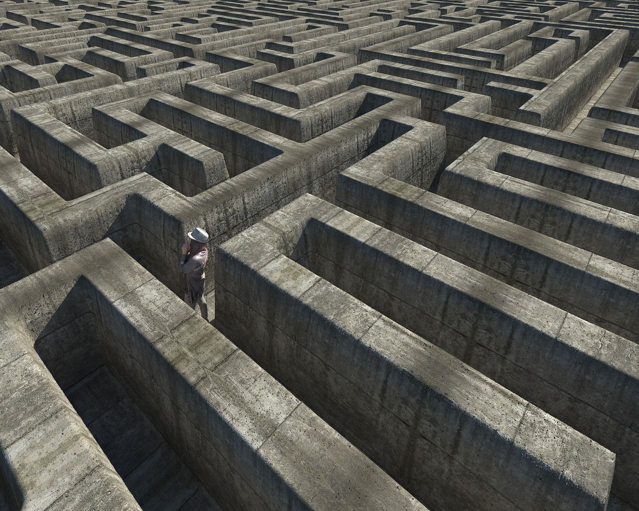 Person navigating a large, gray stone maze.