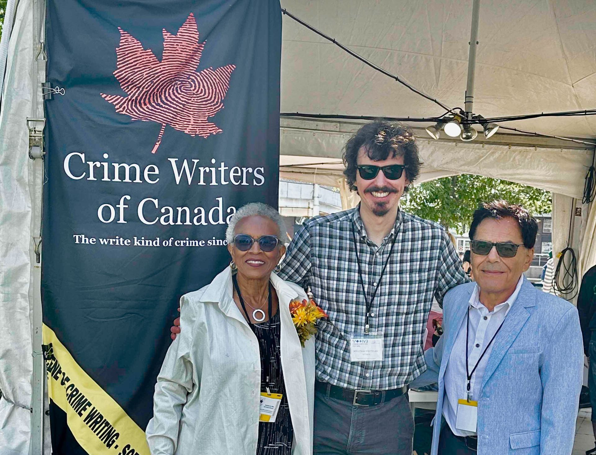 Three people pose in front of a Crime Writers of Canada banner.