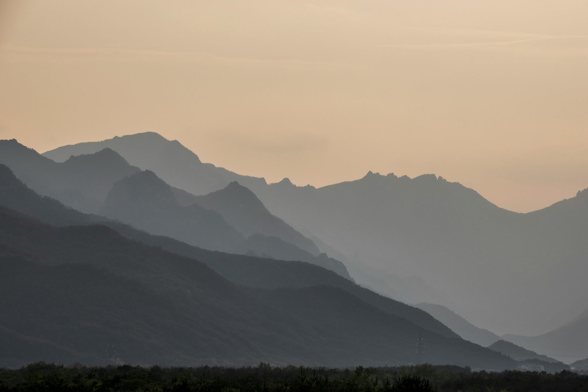 Silhouetted mountain range at dusk, shades of gray and blue against a golden sky.