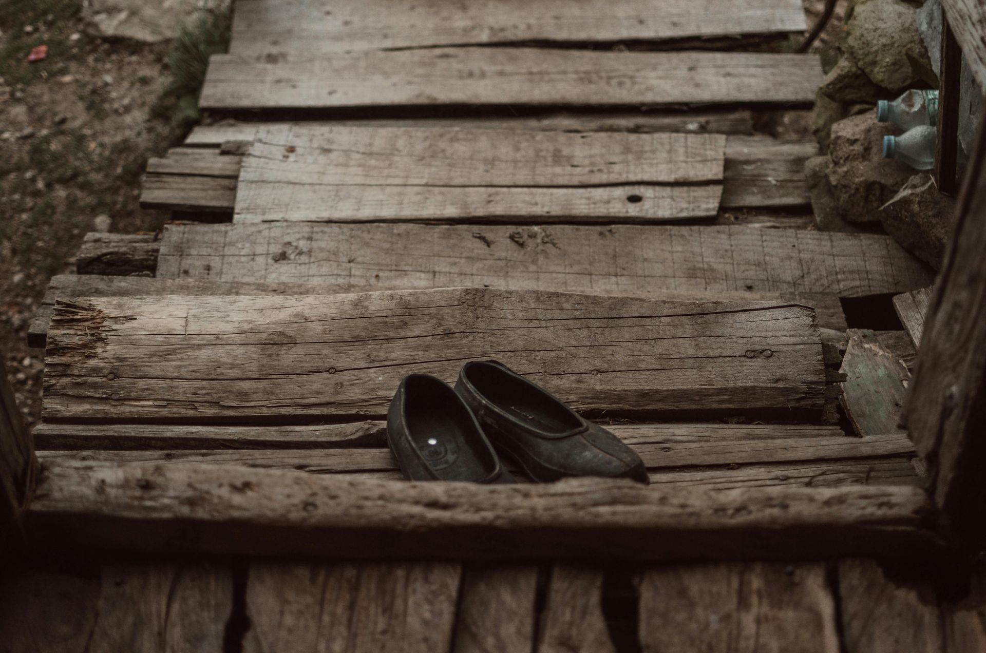 Pair of dark shoes on rustic wooden steps.