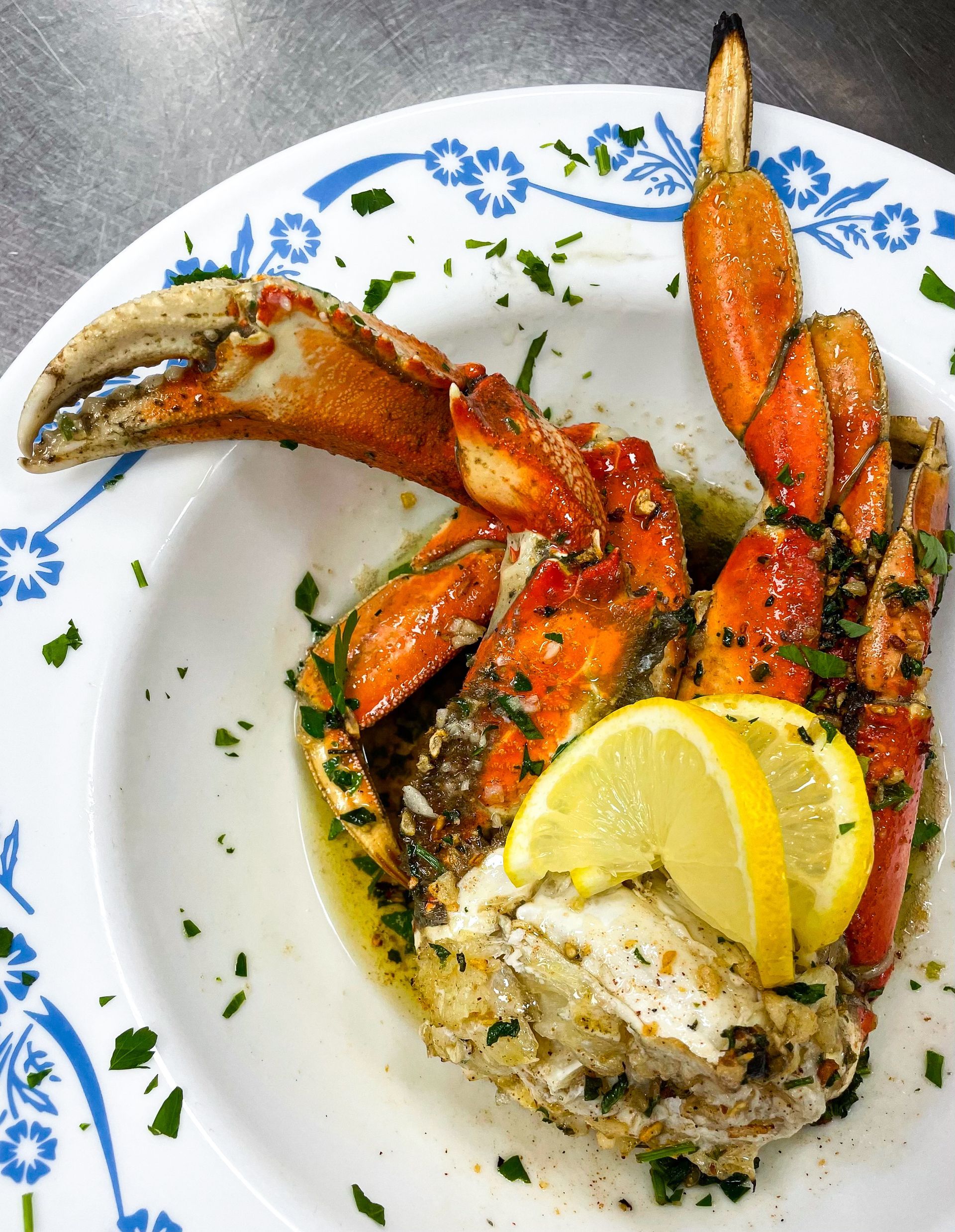 Crab dish with lemon slices and parsley garnish, served on a white plate with a blue floral design.