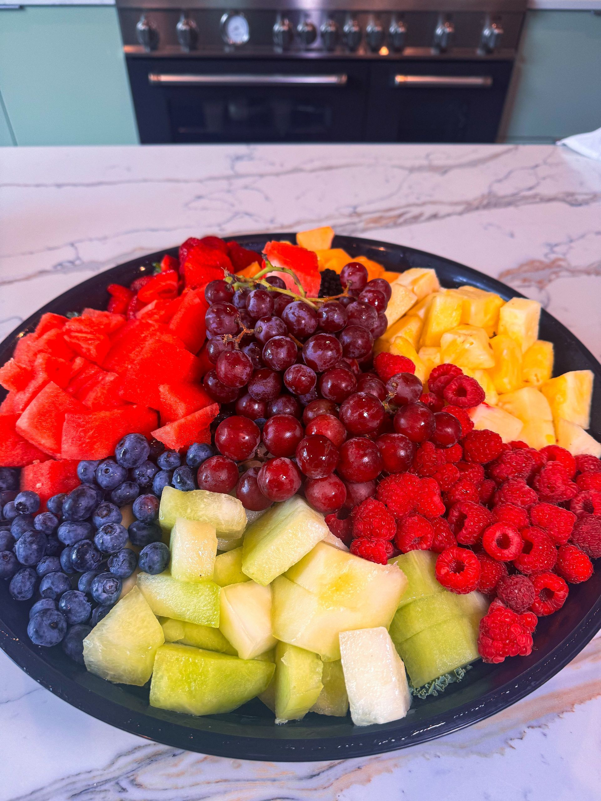 Fruit platter with watermelon, blueberries, grapes, raspberries, cantaloupe, and pineapple.