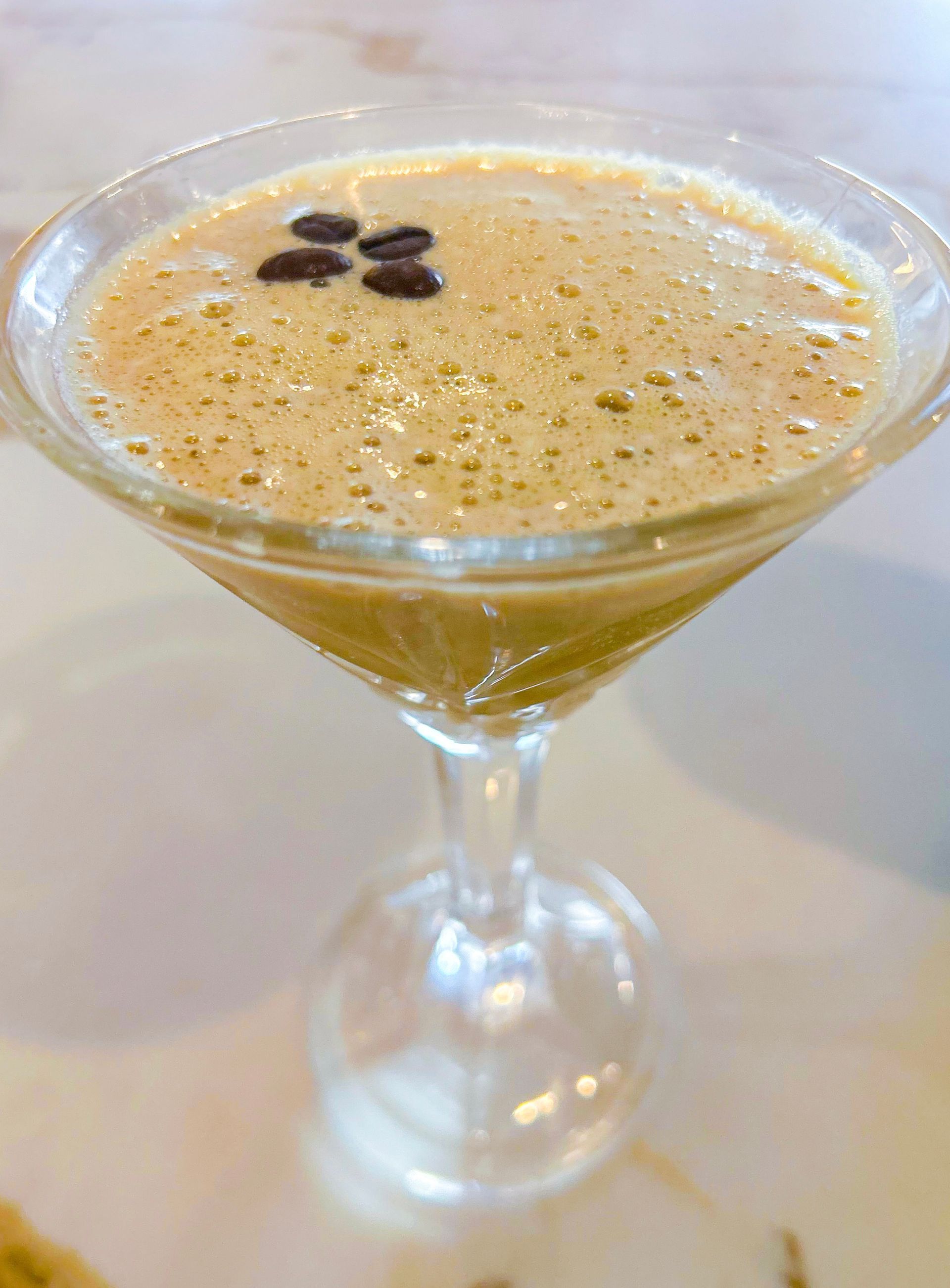 Espresso martini in a clear glass, garnished with coffee beans.