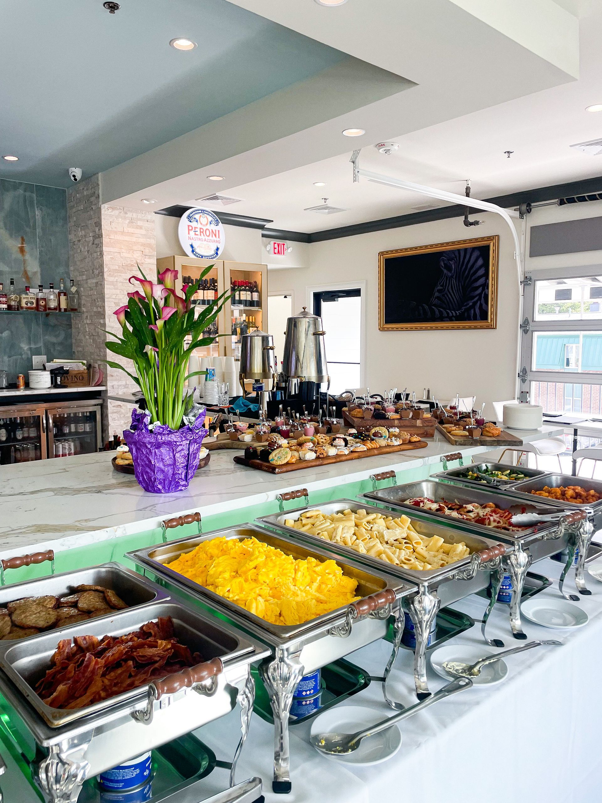 Buffet with various food selections in silver chafing dishes on a long table in a restaurant.