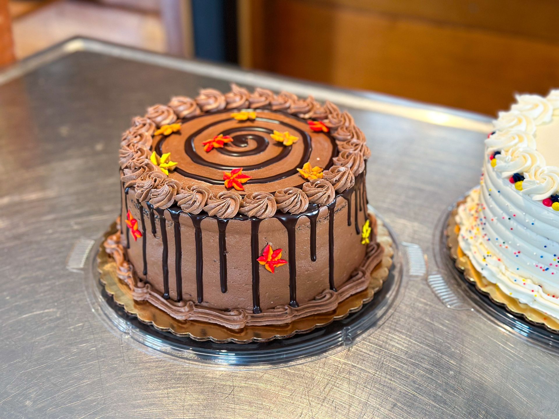 Chocolate cake decorated with dripping frosting, spiral design, and fall leaves.