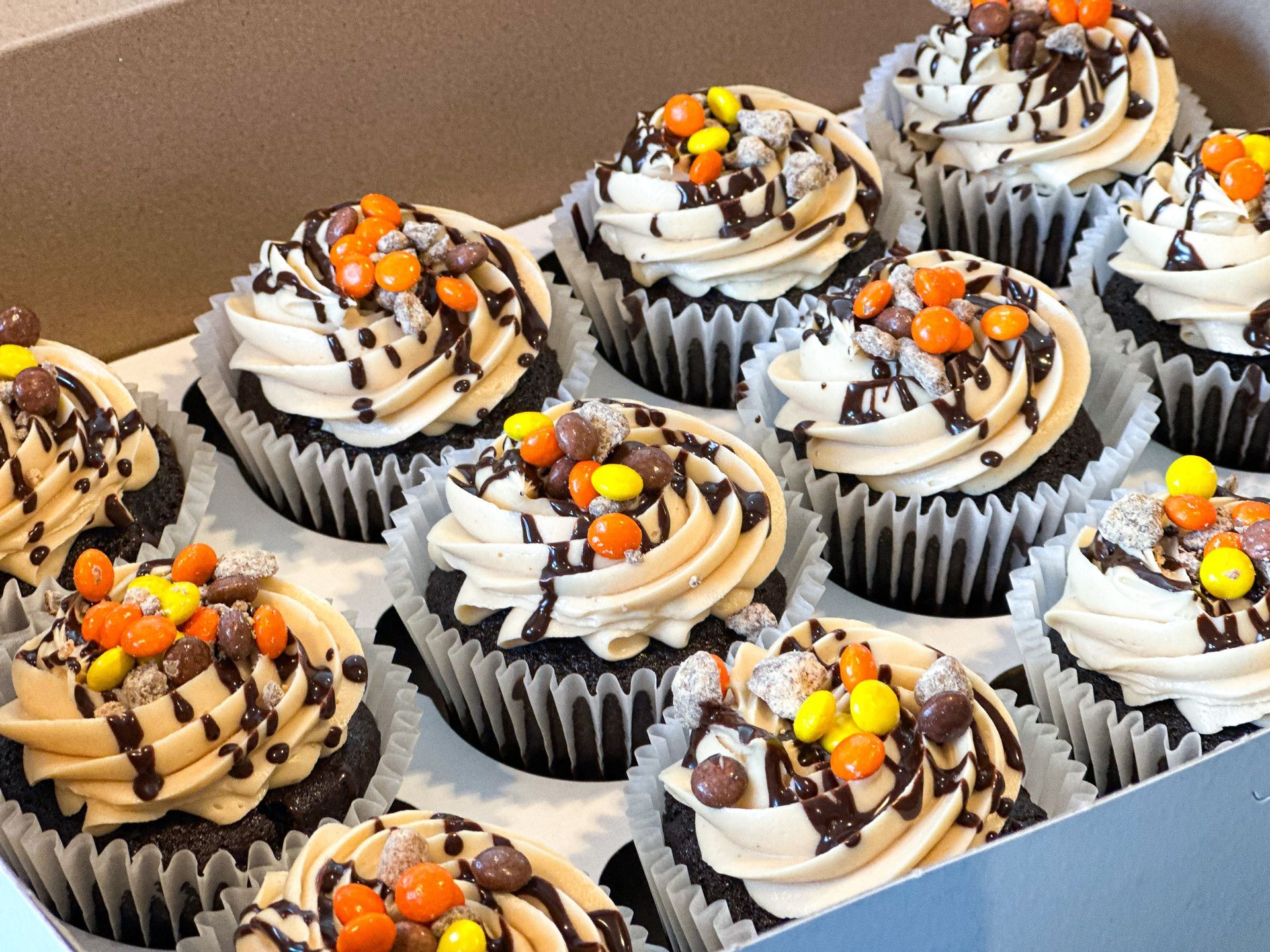 Cupcakes in a box, chocolate frosting, caramel drizzle, candies.