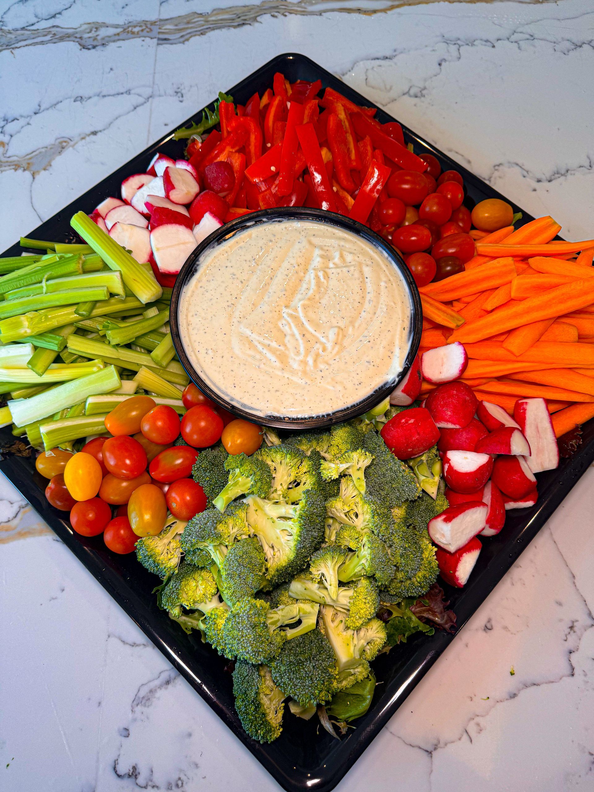 Vegetable platter with assorted raw vegetables arranged around a bowl of dip.