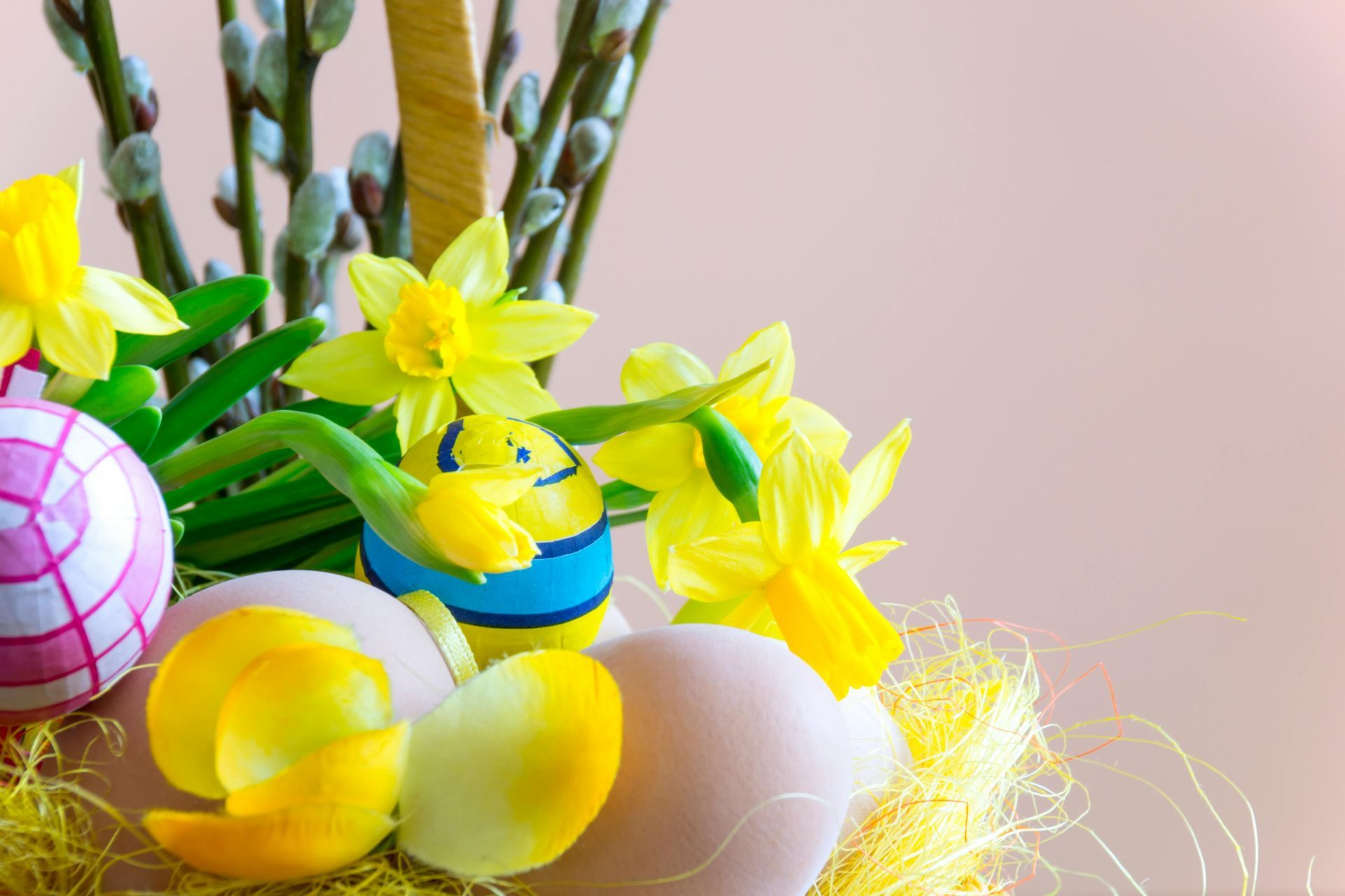 Easter basket with yellow daffodils, painted eggs, and pussy willow branches.