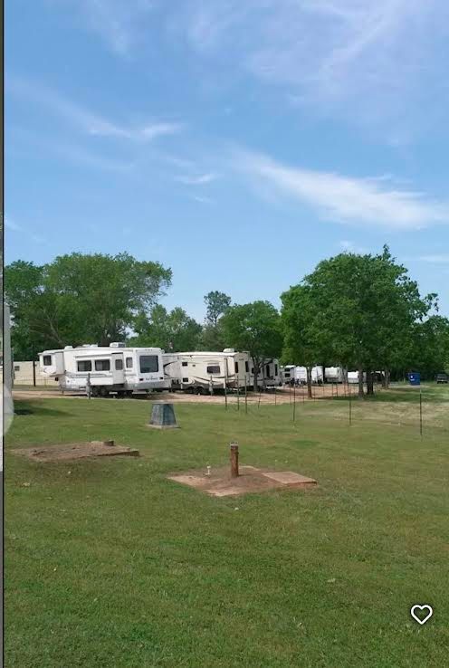 A row of rvs are parked in a grassy field.