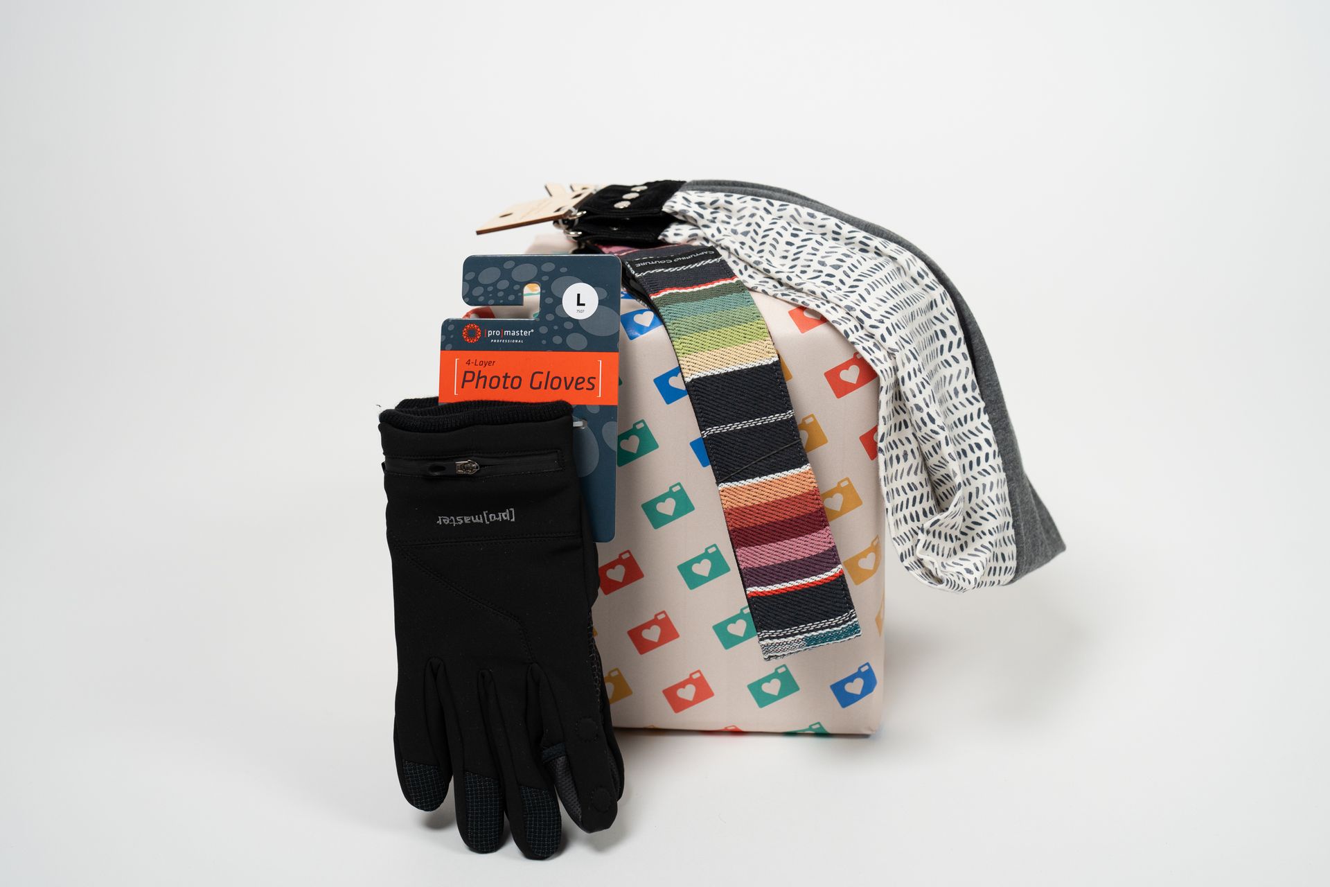 A tie , gloves , and a sweater are sitting on a white surface.