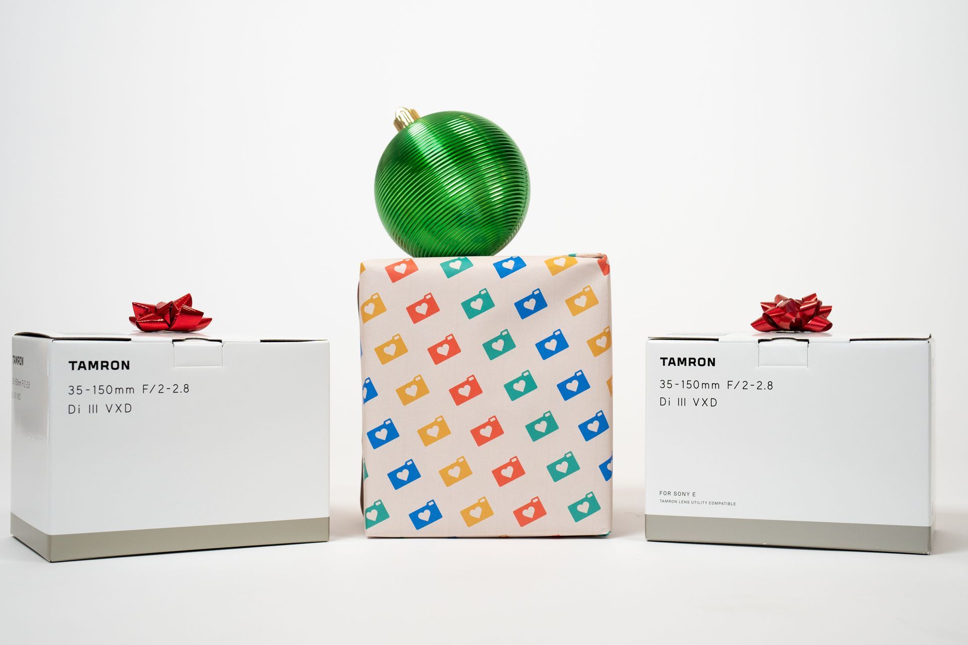 A green christmas ornament is sitting on top of a colorful gift box.