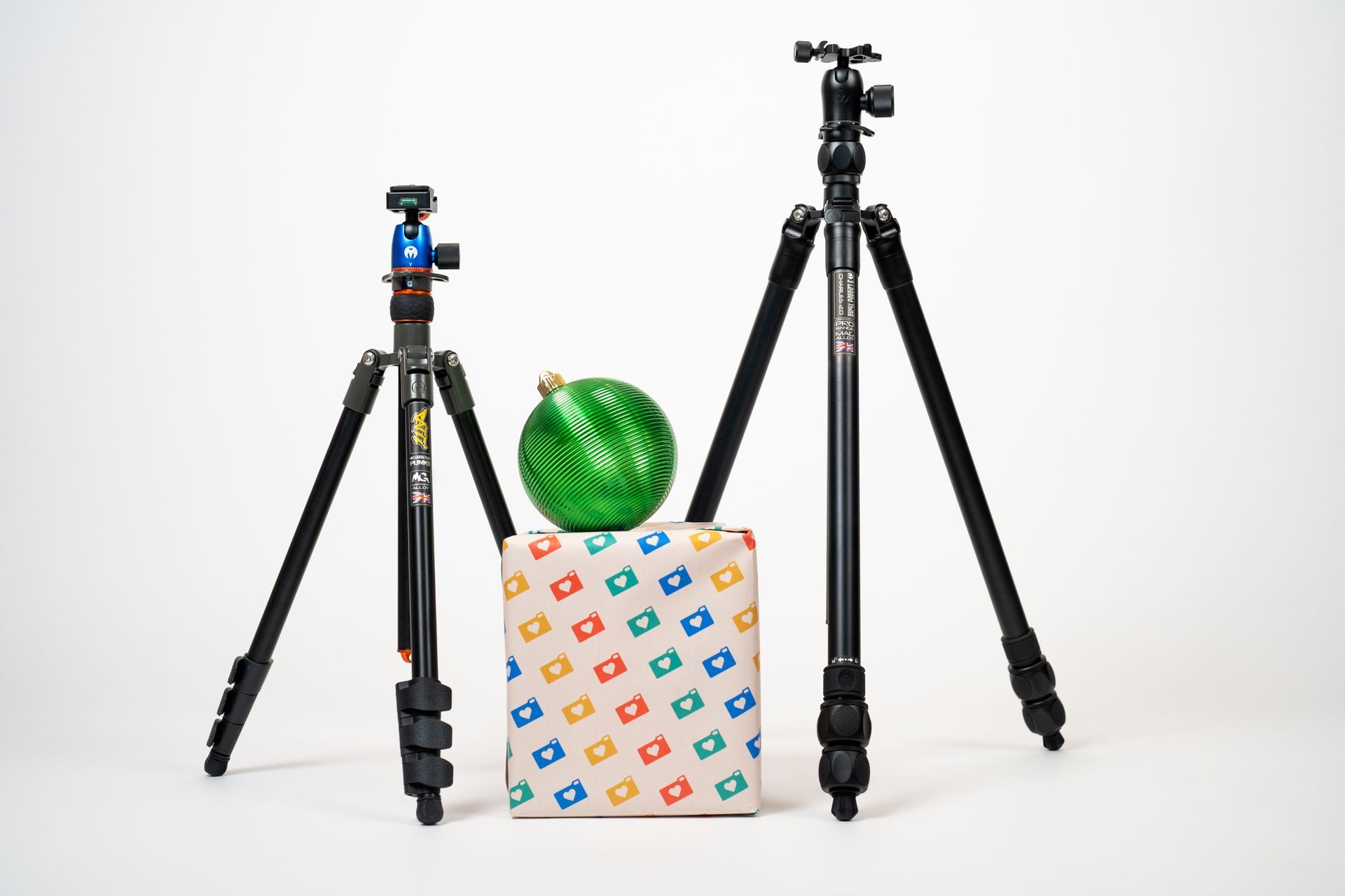 Two tripods and a christmas ornament are sitting next to each other on a white surface.