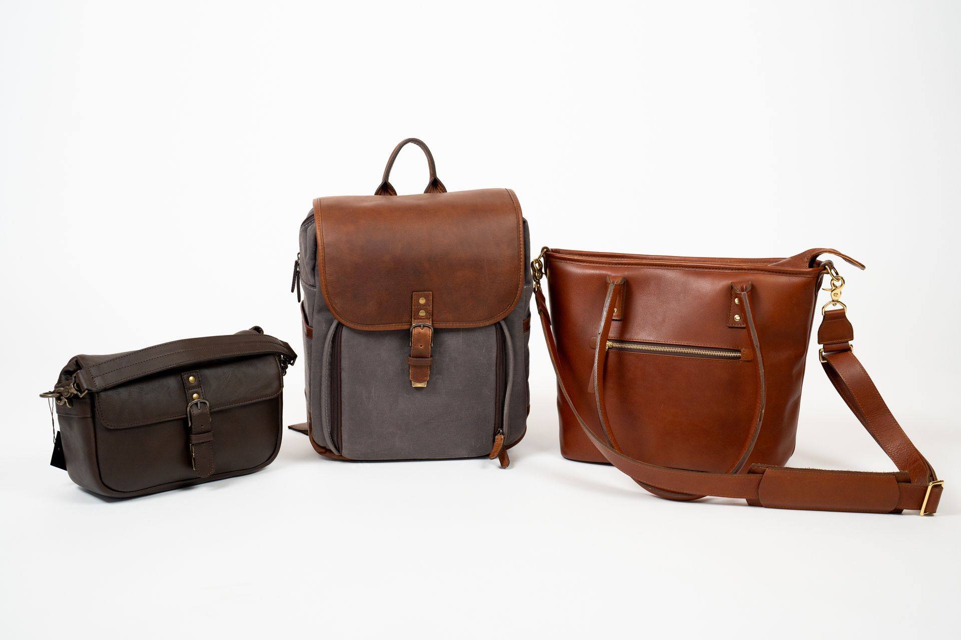 Three leather bags are sitting next to each other on a white surface.