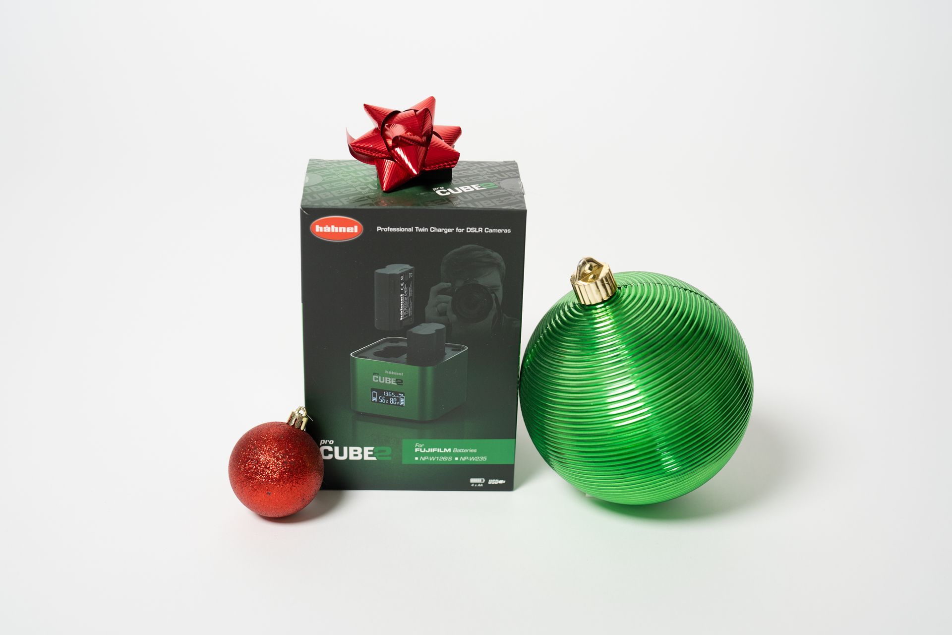 A green christmas ornament is sitting next to a box with a red bow.