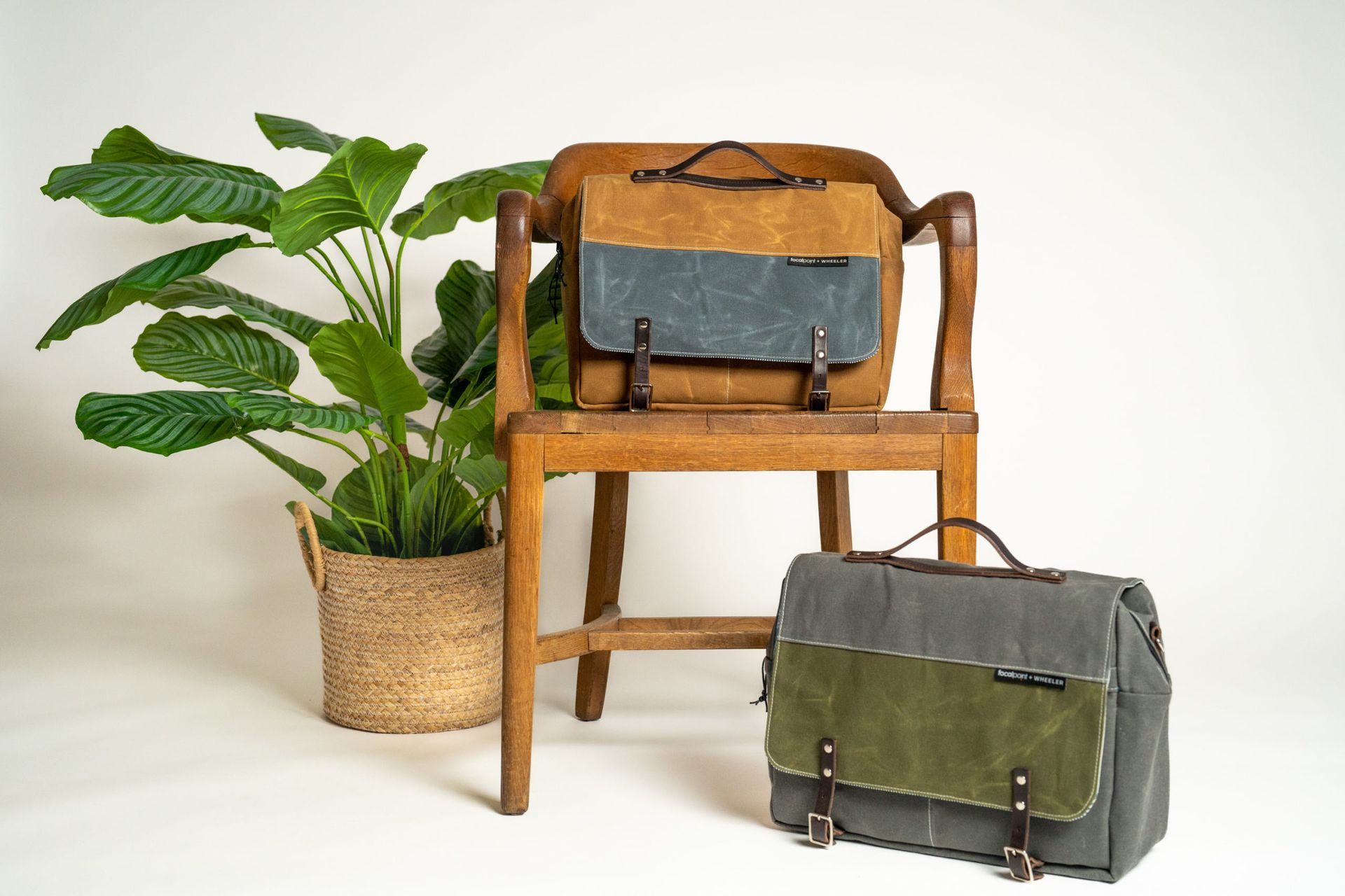 Two bags are sitting on a wooden chair next to a potted plant.